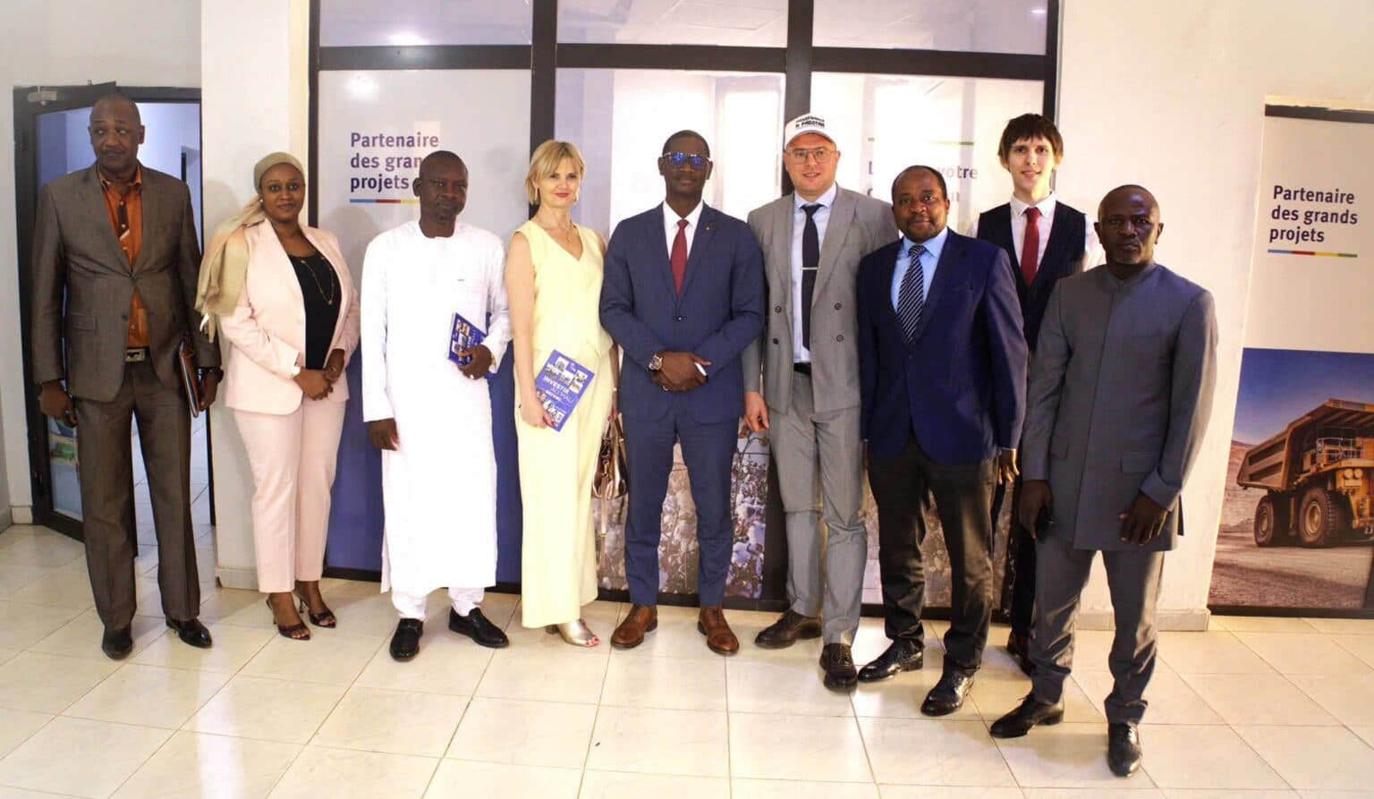 Portrait de groupe de neuf personnes debout dans un hall carrelé devant des kakémonos « Partenaire des grands projets », deux d’entre elles tenant des brochures bleues. — API-Mali